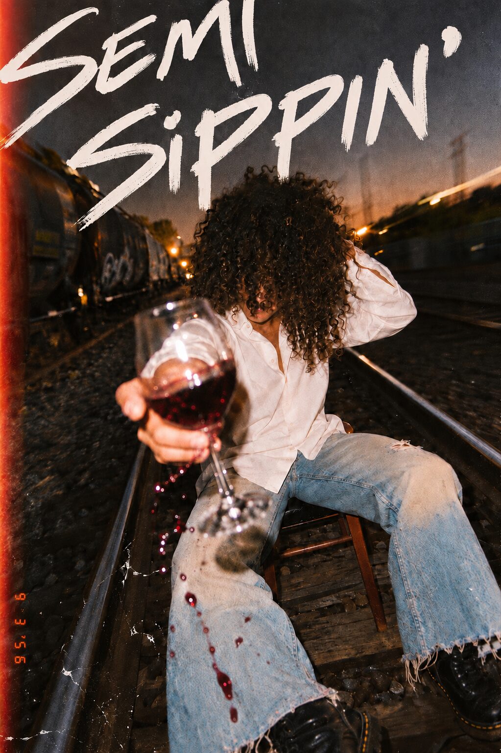 On the railway at dusk, a glass of red wine held out, Semi Sippin' brushed across the top