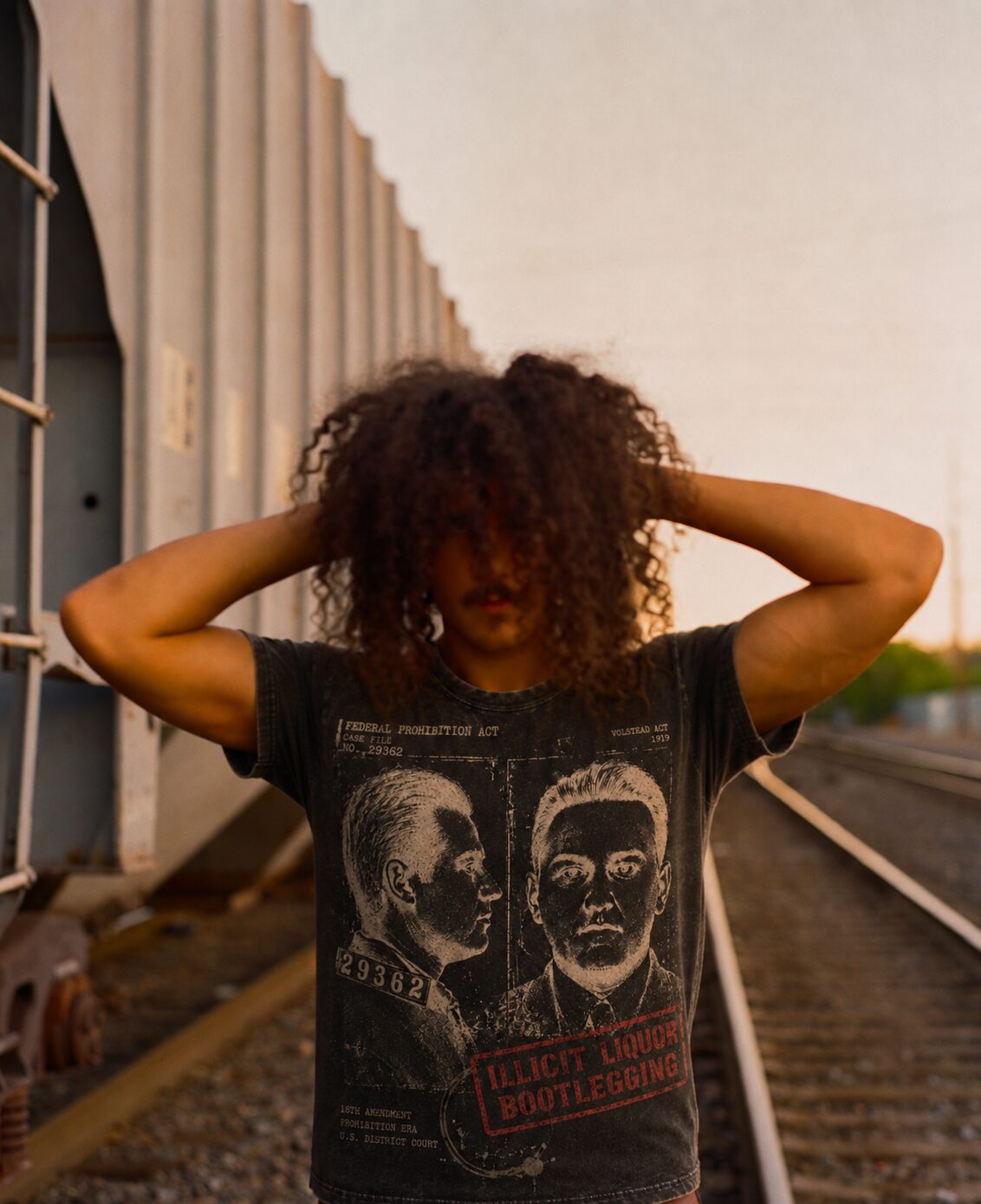 Washed black tee printed with two bootlegging-era mugshots, worn on the railway